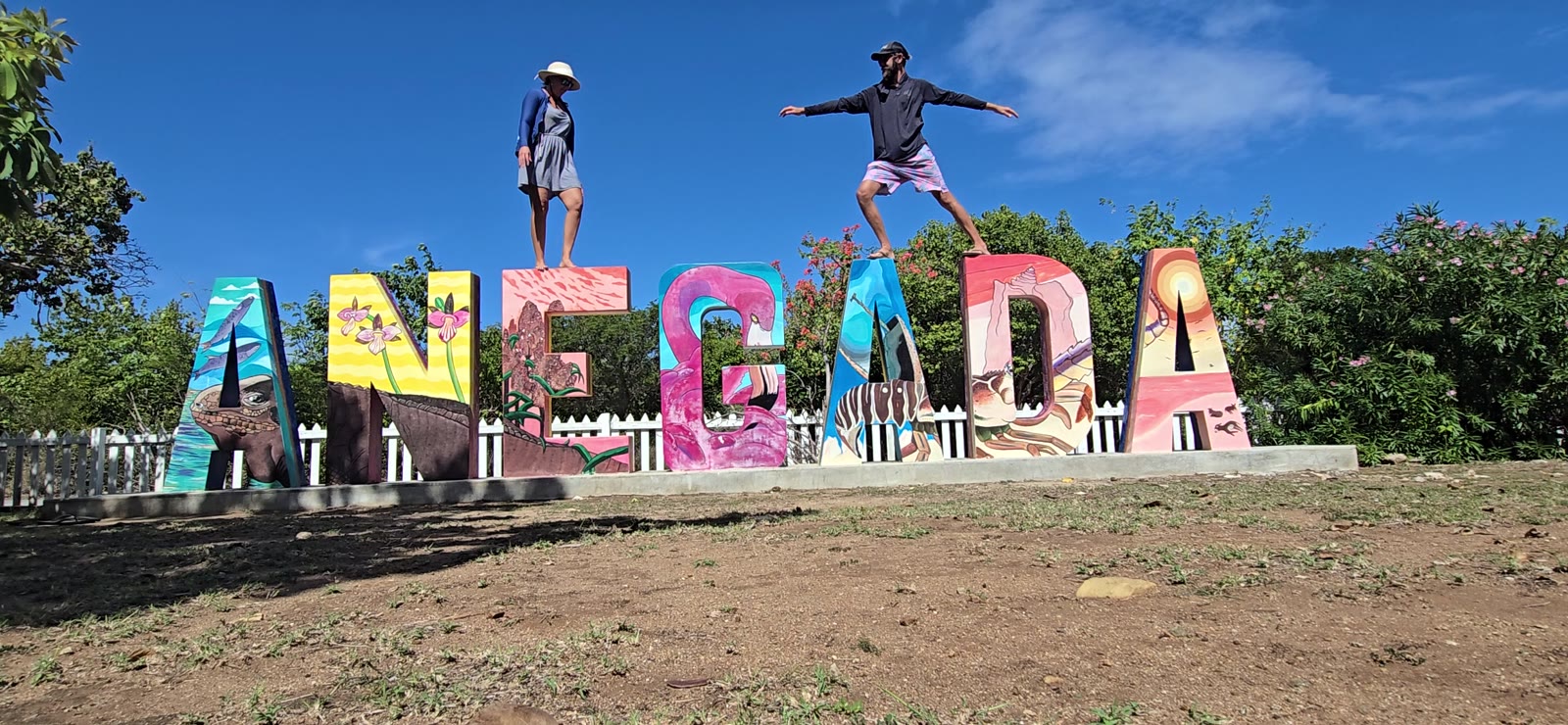 The painted ANEGADA letters near Setting Point, Anegada, with two people standing on top of them