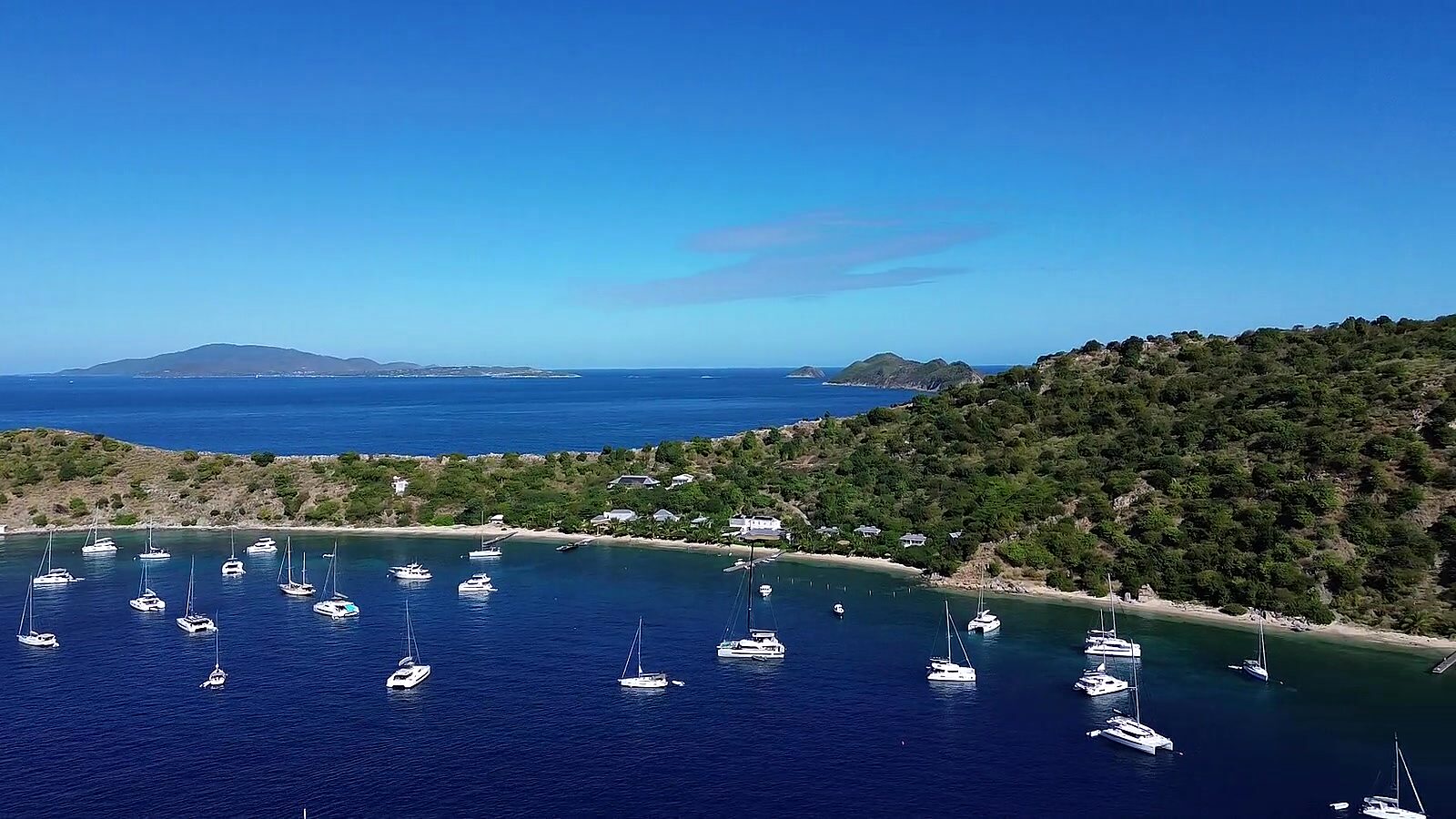 Charter yachts on moorings under the green hillside at Cooper Island, BVI