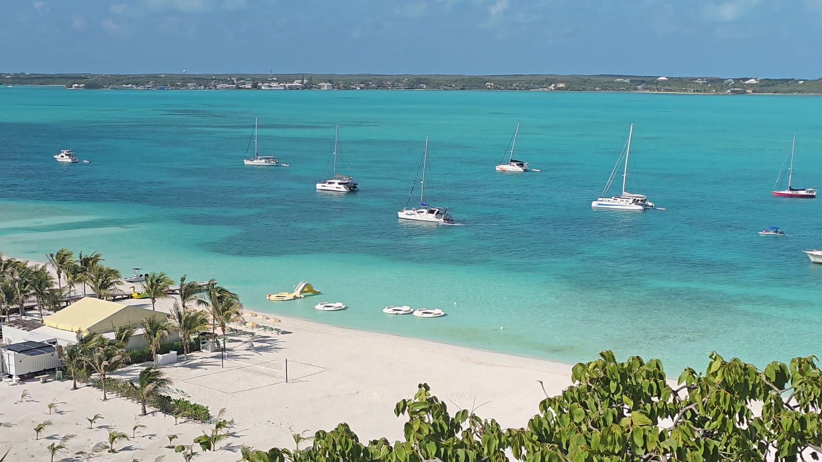 Yachts at anchor in turquoise water off the white beach at Stocking Island, George Town, Great Exuma, seen from the hill above